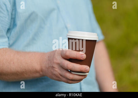 Man's Hand, die eine neue Tasse Kaffee. Trinken auf der Straße Stockfoto