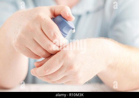 Nahaufnahme der männlichen Händen hält und die Anwendung Weiß Creme von Pumpe Flasche am Zeigefinger Stockfoto