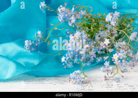 Blaue Vergissmeinnicht liegen auf einem Holztisch Stockfoto
