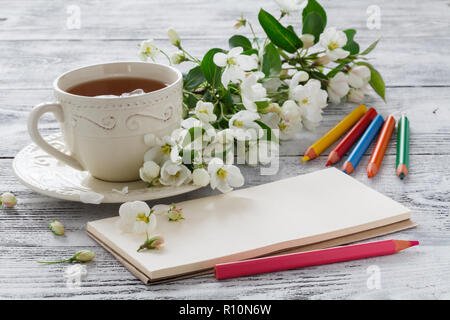 Leere Grußkarte und einer Tasse grüne Blume Kaffee mit Zweigen von Kirsche Blüte auf weißen Holzmöbeln im Landhausstil Hintergrund Stockfoto