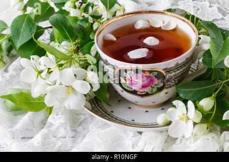 Tasse Tee auf hölzernen Tisch und Apple Blossom. Tee-Zeit-Konzept. Frühstückstasse Tee serviert mit Blumen. Stockfoto