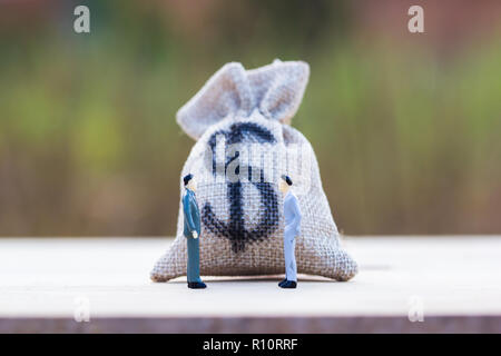 Finanzielle Investitionen Verhandlung, Diskussion unter den CEO oder Konzept ausführen: Geld Beutel auf Holztisch mit Miniatur Figur zwei Geschäftsleute sprechen Stockfoto