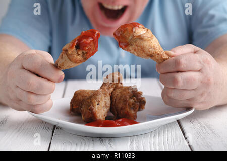 Kaukasische Mann mit Eröffnung Mund über frittierte Hähnchenkeulen oder drumsticks zu essen Stockfoto