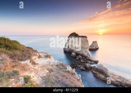Die Faraglioni von Torre Sant'Andrea bei Sonnenaufgang. Melendugno, Provinz Lecce, Salento, Apulien, Italien. Stockfoto