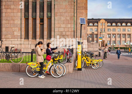 20. September 2018: Helsinki, Finnland - Zwei weibliche asiatische Touristen mit gelb Alepa City Bikes mit Tablet-PC-Karte zu prüfen, bei der zentralen Railwa Stockfoto