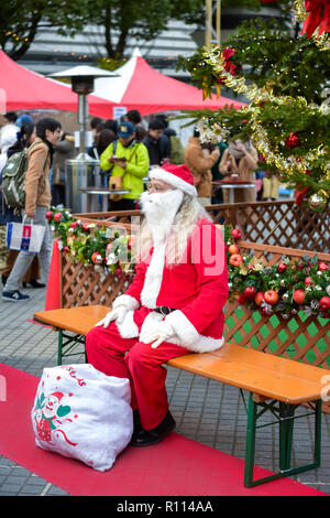 Weihnachten in Japan. Lonely Santa auf einer Bank sitzen. Stockfoto