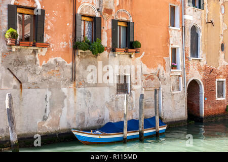 Blau bewaldeten Boot vor der alten Ziegel festgemacht und bemalte Gebäude Venedig Italien Stockfoto