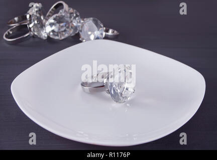 Big Diamond Ring auf dem weißen Teller. Im Hintergrund ein paar Ringe. Stockfoto