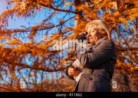 Master walking Mops Hund im Herbst Park. Glückliche Frau umarmen pet. Stockfoto