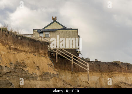 Haus am Rand der Klippe entfernt vom Meer gewaschen, Küstenerosion, globale Erwärmung, Anstieg des Meeresspiegels, Happisburgh Norfolk, Großbritannien. Seitenansicht Stockfoto