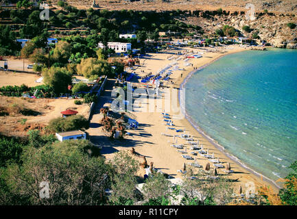 Ein Blick auf den Strand und Liegewiese neben der Stadt Lindos, Rhodos, Griechenland. Stockfoto