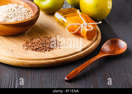 Leinsamen in der Schüssel und Leinsamenöl in Glas Flasche auf Holz- Hintergrund Stockfoto