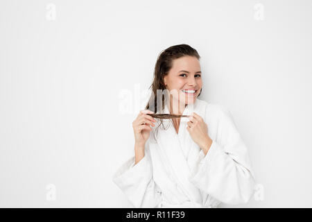 Glückliche junge und natürliche Frau im Bademantel nach einer Dusche, spielte mit ihren nassen Haar und lächelnd Stockfoto