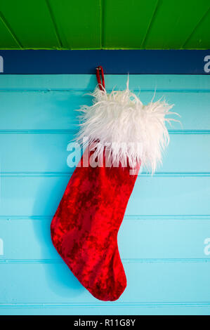 Plüsch red velvet Weihnachtsstrumpf hängen von rustikal Holz Hintergrund in tropischen Farben lackiert Stockfoto