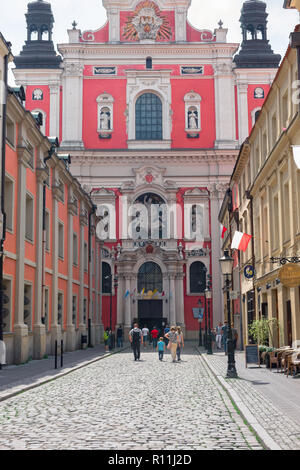 Poznan Straße der Stadt, mit Blick auf die Menschen in der Posener Altstadt zu Fuß in Richtung der barocken Fassade des hl. Stanislaus Pfarrkirche, Polen. Stockfoto