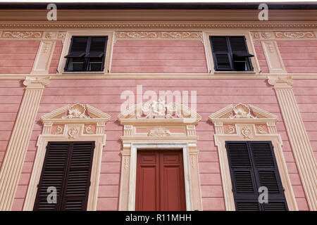 Fensterläden aus Holz sind mit Trompe-l'oeil-Säulen und Rahmen auf diesem Gebäude in Sestri Levante eingerichtet. Stockfoto