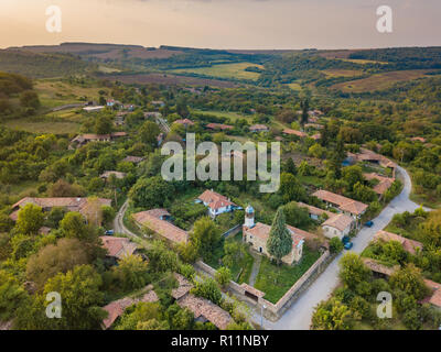 Luftaufnahmen von Eine kleine orthodoxe christliche Dorf im Norden von Bulgarien - kleine Kirche, typische Häuser - wunderschönen Sonnenaufgang in einer entspannten ländlichen Stockfoto