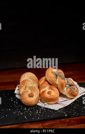 Frisch Mohn, seasame Saatgut und Brot braid auf schwarzen Stein schneiden, mit Sesam bestreut. Sehr geringe Tiefenschärfe Stockfoto