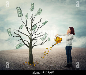 Junge Frau mit der Gießkanne Gießen eine Anlage mit goldenen Münzen ein Dollar anzuheben Rechnungen Geld Baum. Financial Management, Business wächst, investme Stockfoto