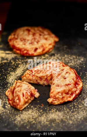Frisch Geback mit Schinken, Käse und Tomaten Soße auf schwarzen Stein Schneidbrett. Sehr geringe Tiefenschärfe Stockfoto