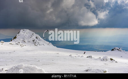 Dramatische Landschaft auf einem gefrorenen Berg - Parasailing unter den Strahlen der untergehenden Sonne mit der wunderschönen Kulisse auf Schnee und Fels Stockfoto