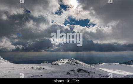 Dramatische Landschaft auf einem gefrorenen Berg - Parasailing unter den Strahlen der untergehenden Sonne mit der wunderschönen Kulisse auf Schnee und Fels Stockfoto