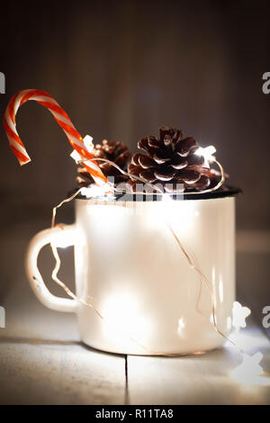 Tannenzapfen in Zinn Glas mit funkelnden sternförmige Garland und einzelne Zuckerstange stick. Weihnachtsschmuck. Stockfoto