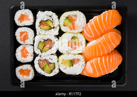 Maki und Nigiri Sushi auf schwarzen Hintergrund. Ansicht von oben Stockfoto