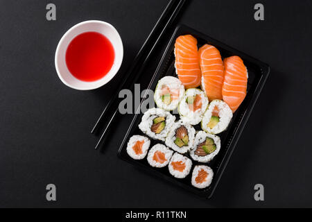 Maki und Nigiri Sushi auf schwarzen Hintergrund. Ansicht von oben Stockfoto