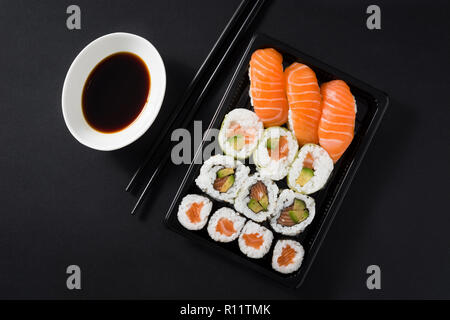 Maki und Nigiri Sushi auf schwarzen Hintergrund. Ansicht von oben Stockfoto