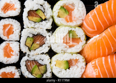 Maki und Nigiri Sushi auf schwarzen Hintergrund. Ansicht von oben Stockfoto