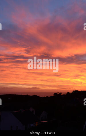 Untergehende Sonne auf Mumbles, Gower, erzeugt einen schönen farbigen Himmel von einzigartigen atmosphärischen Bedingungen, die intensiven Farben Orange und Rot Stockfoto