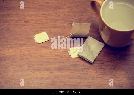 Tasse Tee mit Teebeutel auf braunen Tisch Hintergrund Textur Stockfoto