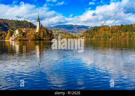 Panoramablick auf den Bleder See mit Kirche und Pletna, Slowenien und im Herbst bunte Bäume Hintergrund Stockfoto