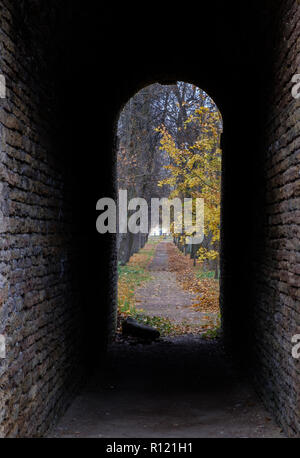 Blick auf den Herbst Park durch einen Steinbogen. Weg in eine andere Welt Stockfoto