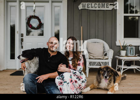 Paare und ihre zwei Hunde sitzen auf der Veranda Stockfoto