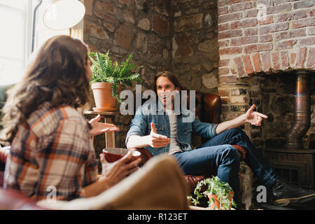 Mitte - erwachsene Paare sitzen in einem kleinen Café entspannen. Sie sitzen auf den Ledersofas und genießen einen Kaffee, während im Gespräch. Stockfoto