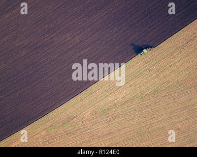 Luftbild von einem Traktor pflügen ein Feld in einer Landschaft, Land Business Konzept. Pflügen im Herbst, Drone erschossen. Stockfoto