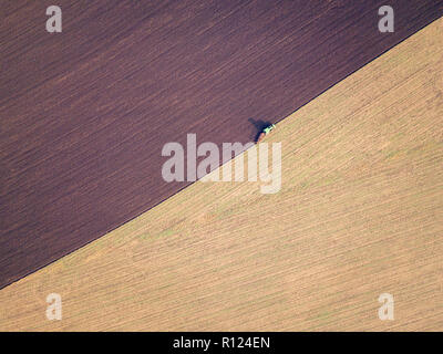 Luftbild von einem Traktor pflügen ein Feld in einer Landschaft, verschwommene Bewegung mit Fokus auf Traktor. Pflügen im Herbst, Drone erschossen. Stockfoto