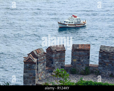 Blick von der Festungsmauer von einem kleinen Boot auf dem Meer Oberfläche. Teil des Turms der berühmten Burg Rumeli Hisari auf dem Bosporus, Istanbul Stockfoto