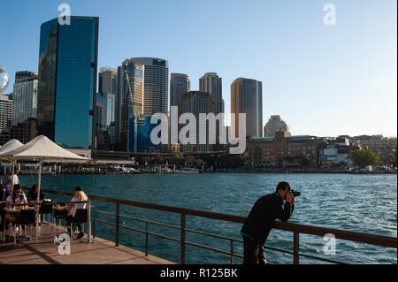 19.09.2018, Sydney, New South Wales, Australien - ein Mann ist das Fotografieren an der Uferpromenade entlang Circular Quay mit der Central Business District Stockfoto