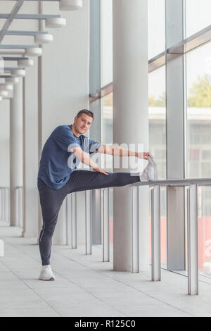 Sportliche Läufer tun stretching Übung in einem Sportzentrum, Vorbereiten für Morgen Workout. Stockfoto
