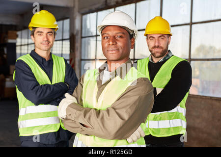 Drei Lagerarbeiter als stolzer internationale Logistik Team in einem Lager Stockfoto