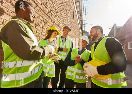 Gruppe der Arbeitnehmer als Logistik Team vor einer Fabrik Spaß hat und lacht zusammen Stockfoto