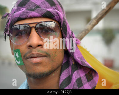 Junge Indische muslimische Mann mit grünem Glitter auf seine Wangen trägt aviator Sonnenbrille und einem karierten Kopftuch, während der Rabi' al-Awwal Festlichkeiten. Stockfoto