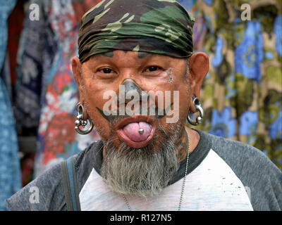 Thai Mann mit aufwendigen facial Tattoos und interessante Ohr und Zunge Piercings. Stockfoto