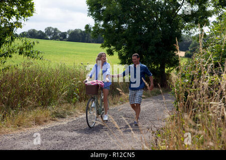 Reifes Paar Spazierengehen und Radfahren auf ländlichen Straßen Stockfoto