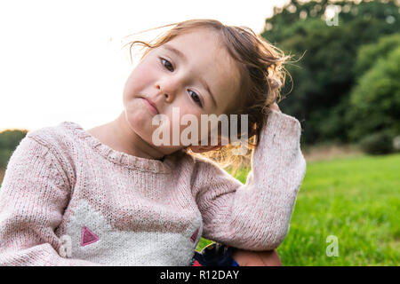 Kind sitzen auf Gras im Park Stockfoto