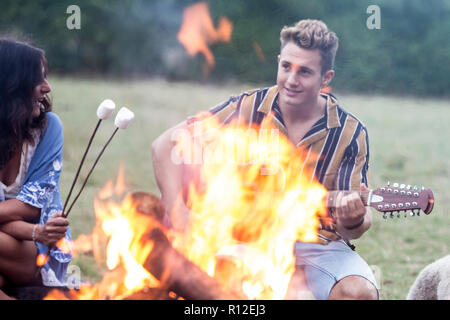 Junger Mann Gitarre zu spielen, Lagerfeuer Party im Park Stockfoto