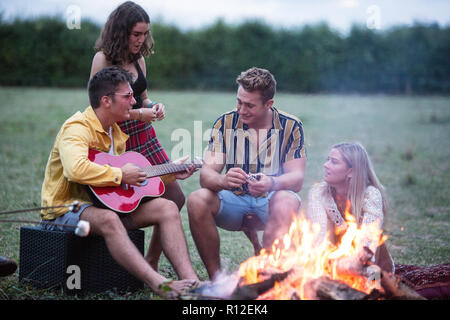 Junger Mann Gitarre zu spielen, Lagerfeuer Party im Park Stockfoto